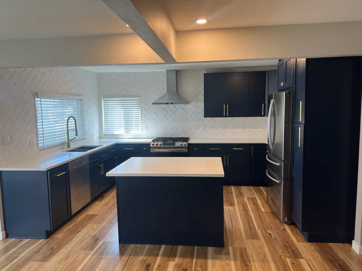 Newly renovated kitchen in Denver with blue cabinets, blue island, white walls, and new wood flooring