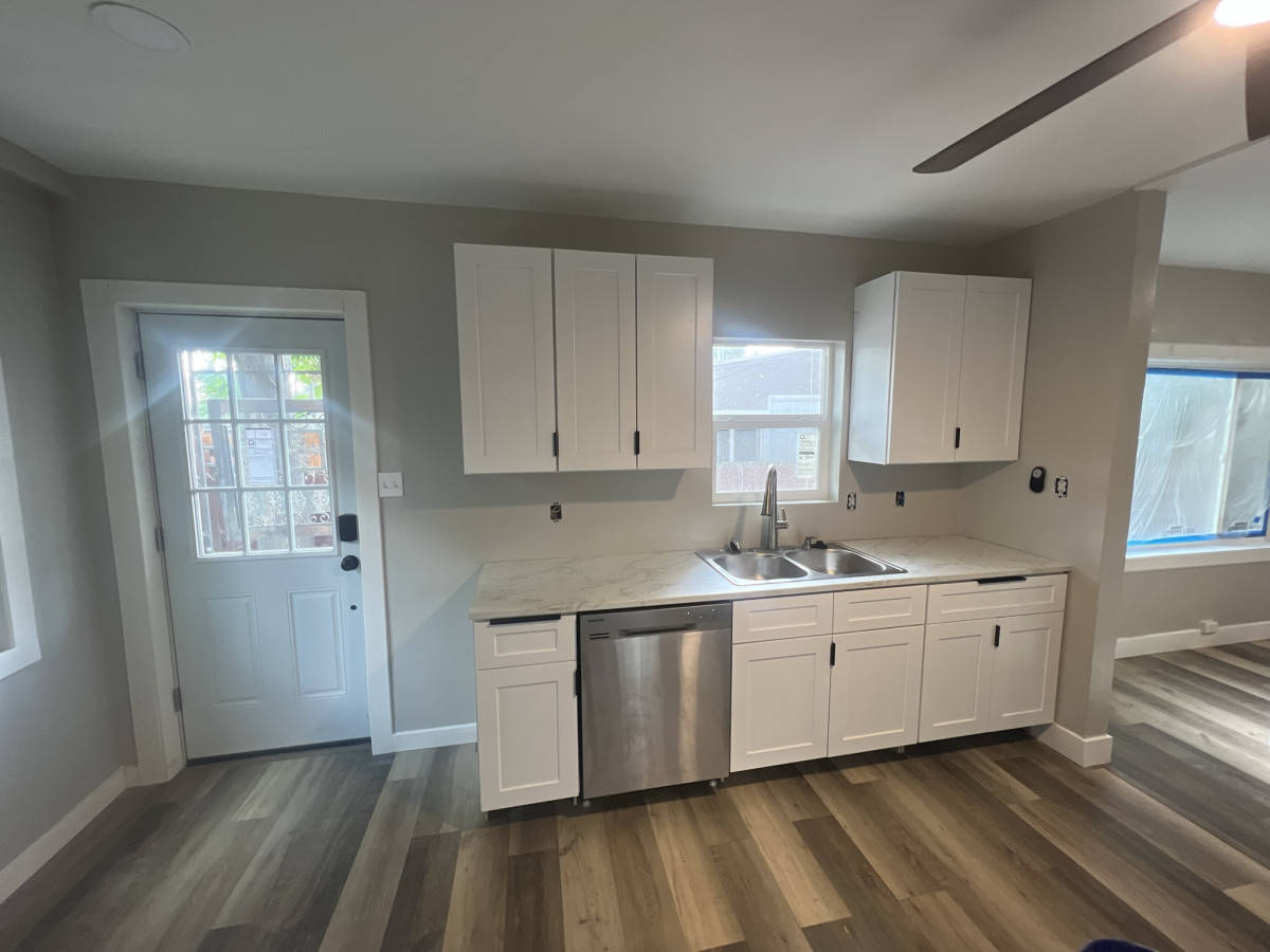 Remodeled Kitchen With White Cabinets Finished kitchen remodel in Denver. Kitchen has new white cabinets, new wood floor, and new windows.